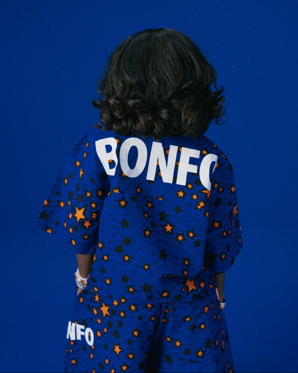 Person wearing a blue African outfit with 'BONFO' text on the back against a blue background